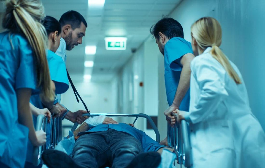 急诊护理执业护士帮助医疗团队移动轮床上的病人